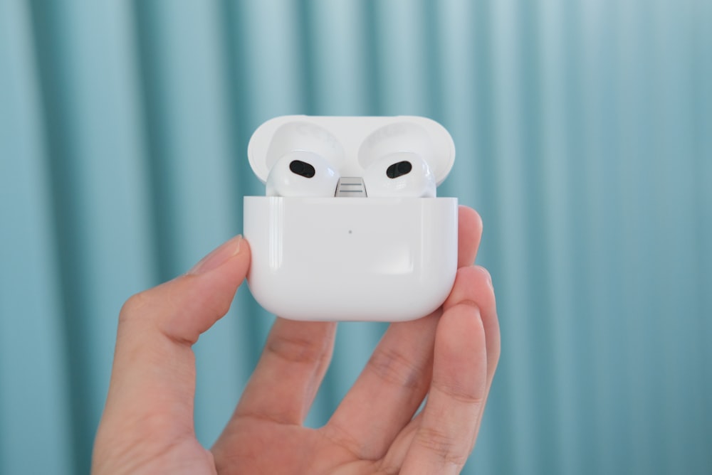 a person holding an airpods in their hand