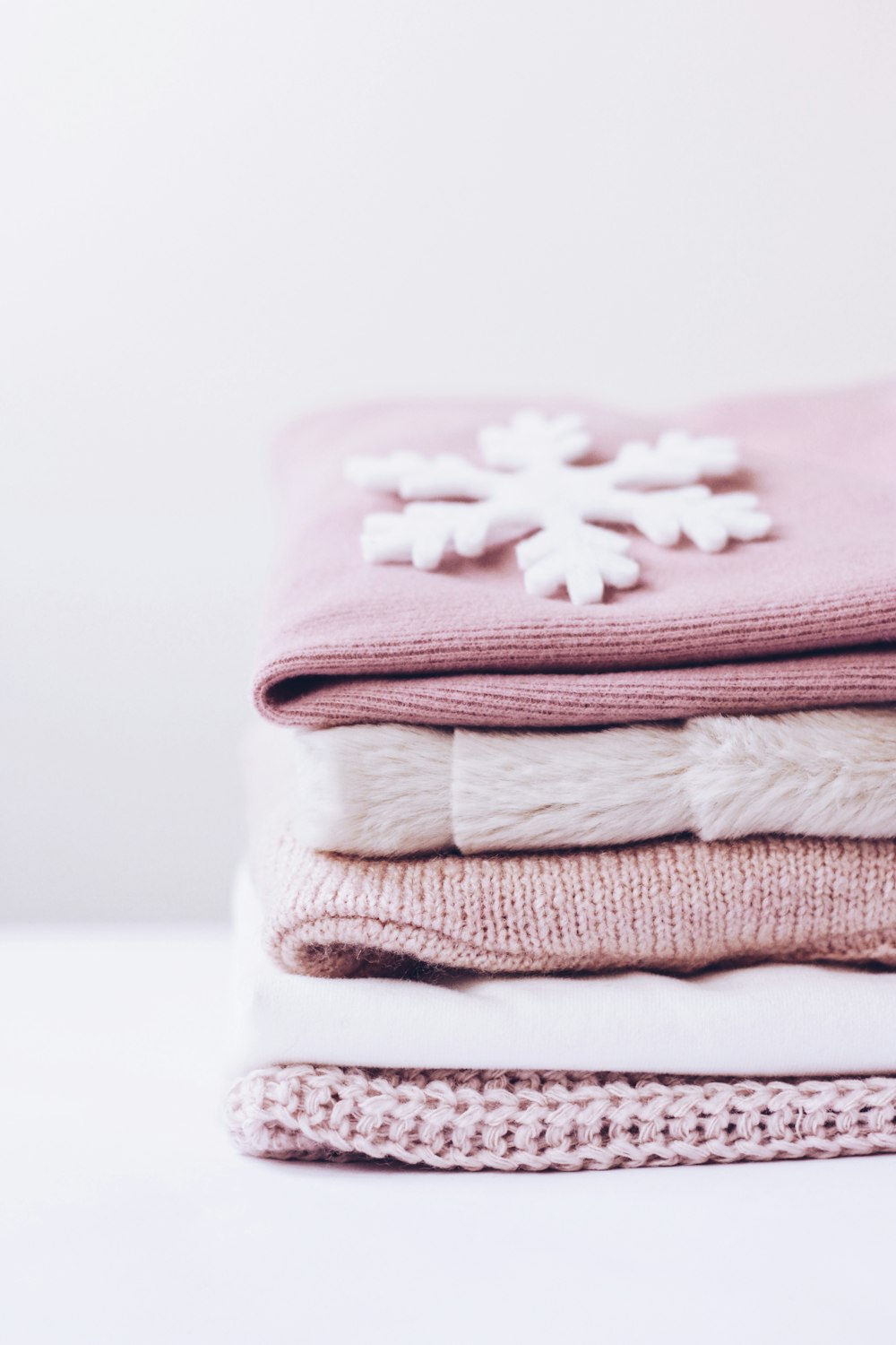 a stack of folded sweaters with a snowflake on top