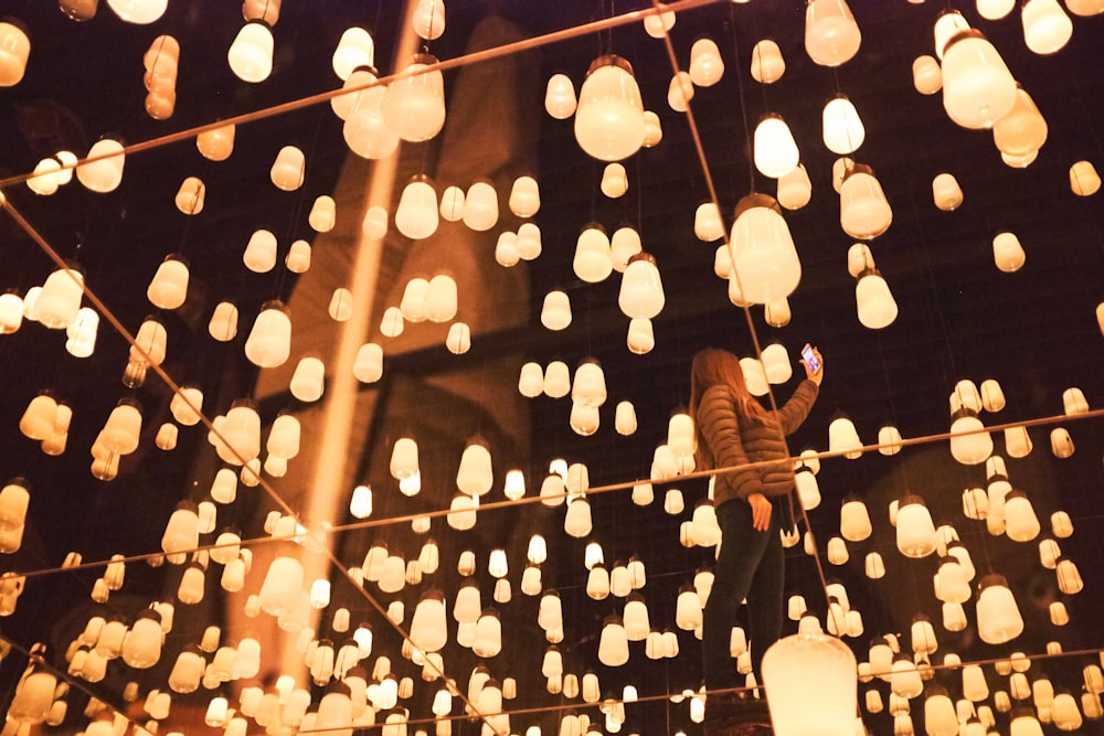 Una persona parada en una cuerda con muchas luces en el fondo