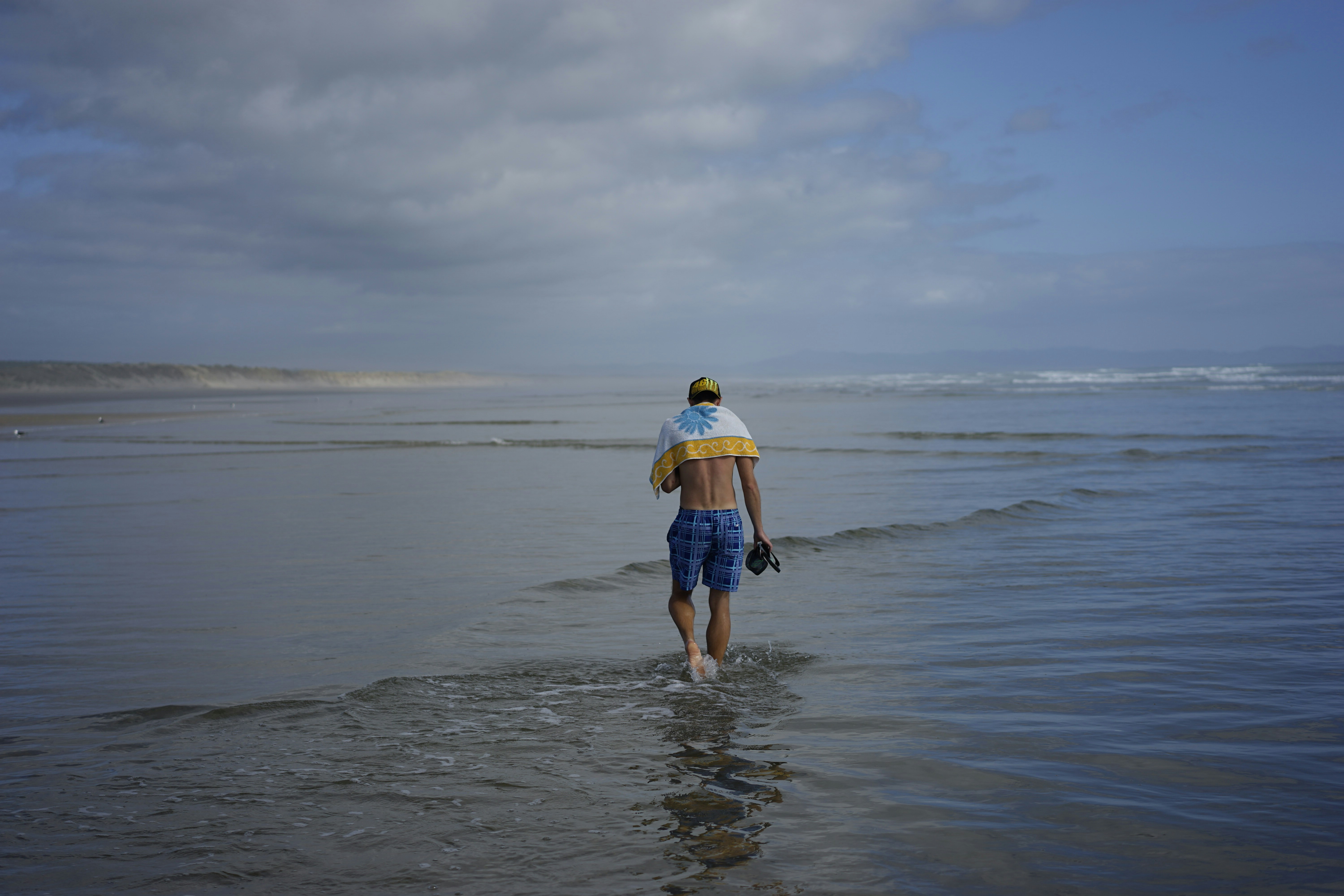 a man walking into the ocean with a surfboard