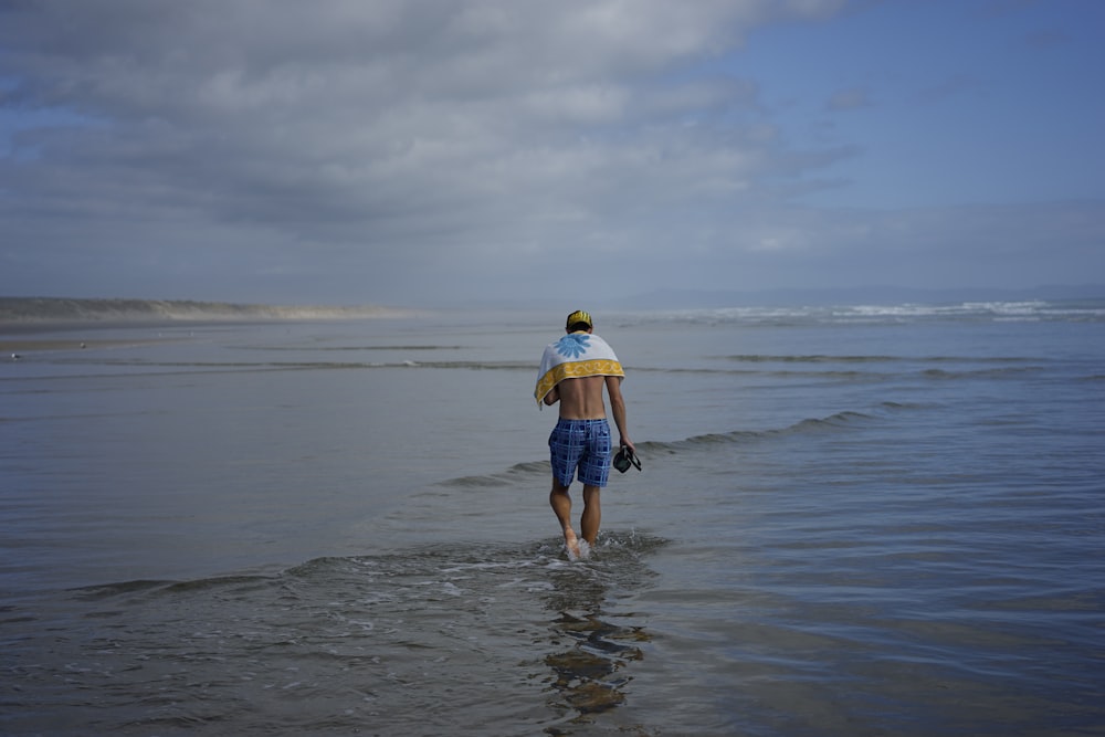 a man walking into the ocean with a surfboard