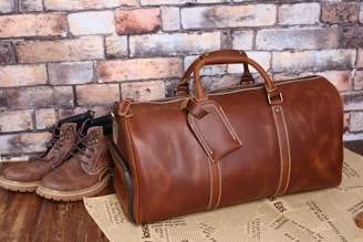 a brown leather duffle bag sitting on top of a wooden table