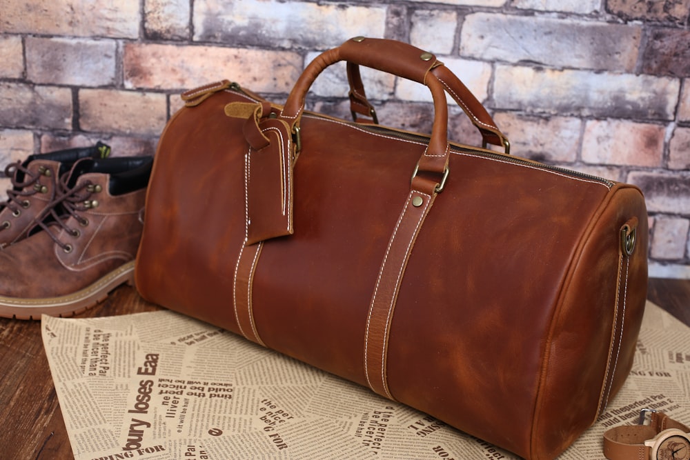 a brown leather duffel bag sitting on top of a table