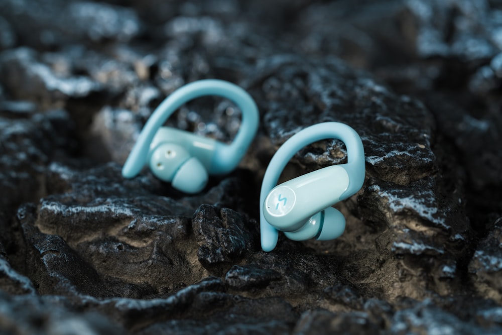 a pair of blue ear buds sitting on a rock