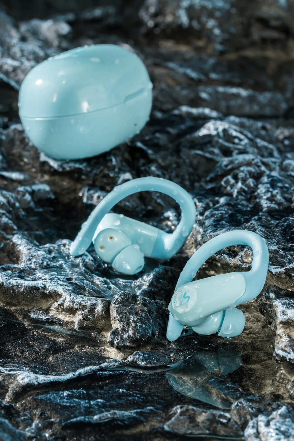 a pair of blue ear buds sitting on top of a rock