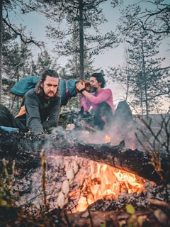 A veteran and his dog share a quiet moment by a sunlit campfire in the backcountry.