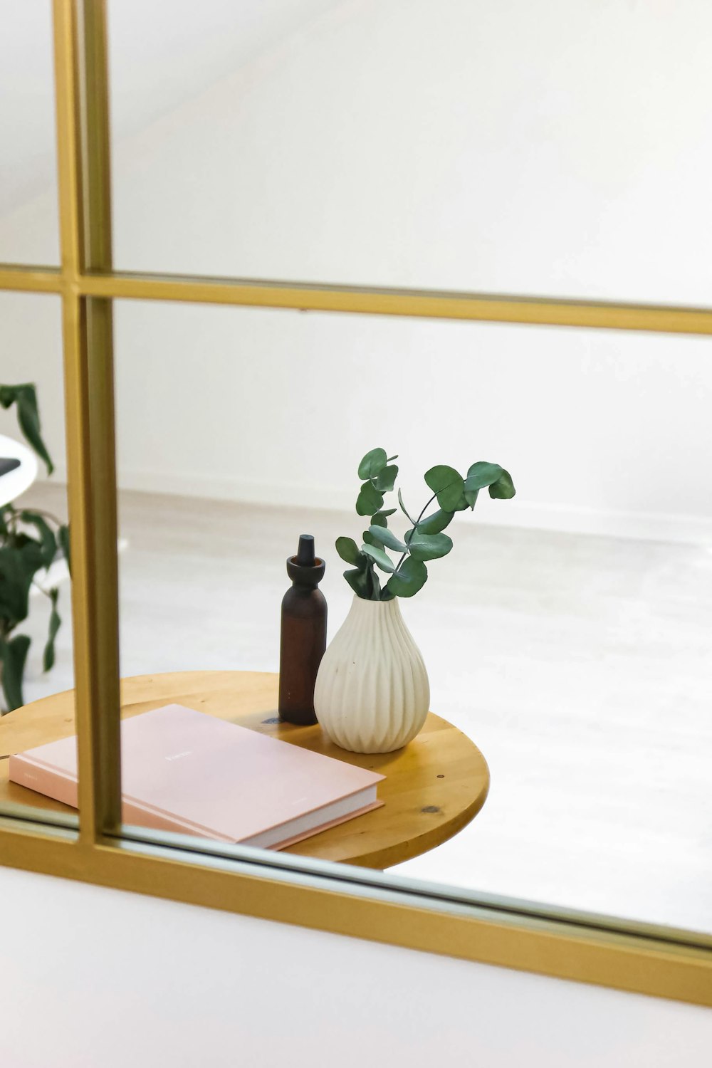 a table with a mirror and a vase with a plant on it