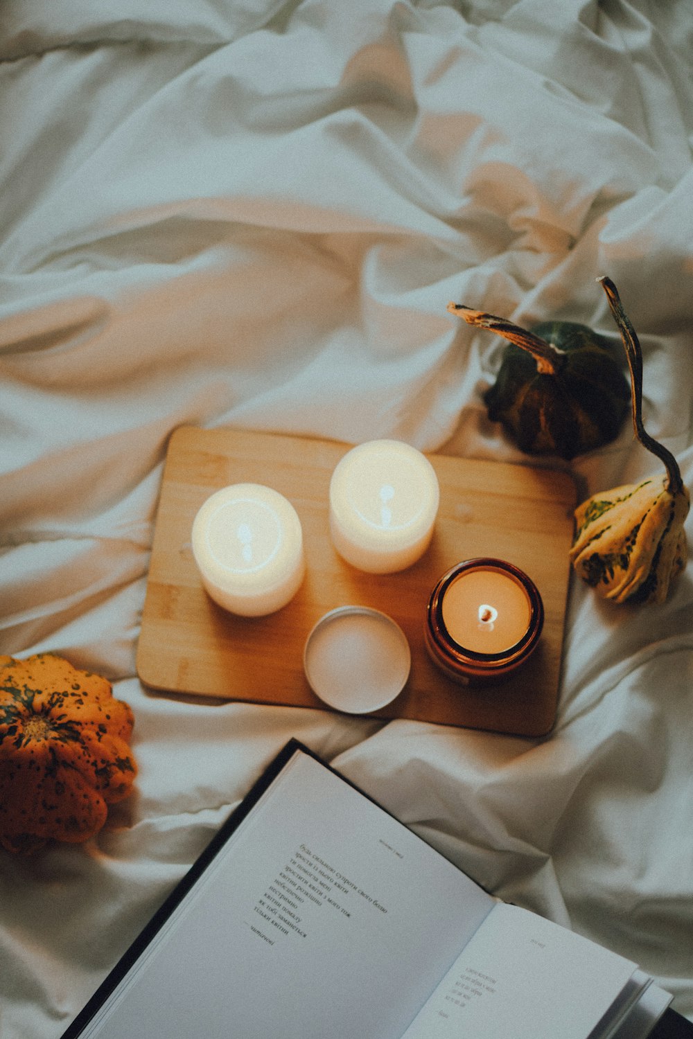 two candles and a book on a bed