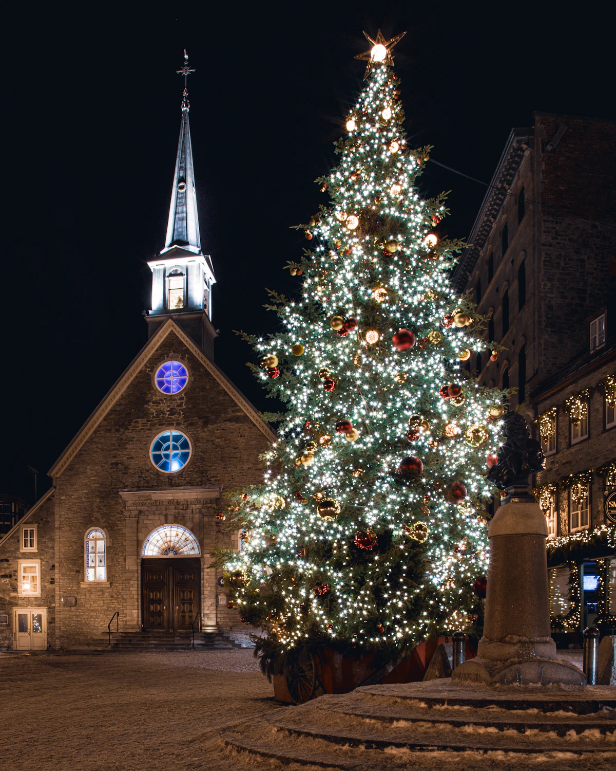 Stone church with a lit Christmas tree in Place Royale, Québec City