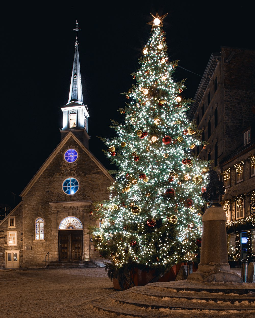 a lit christmas tree in front of a church