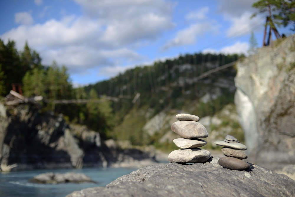 a pile of rocks sitting on top of a rock next to a river