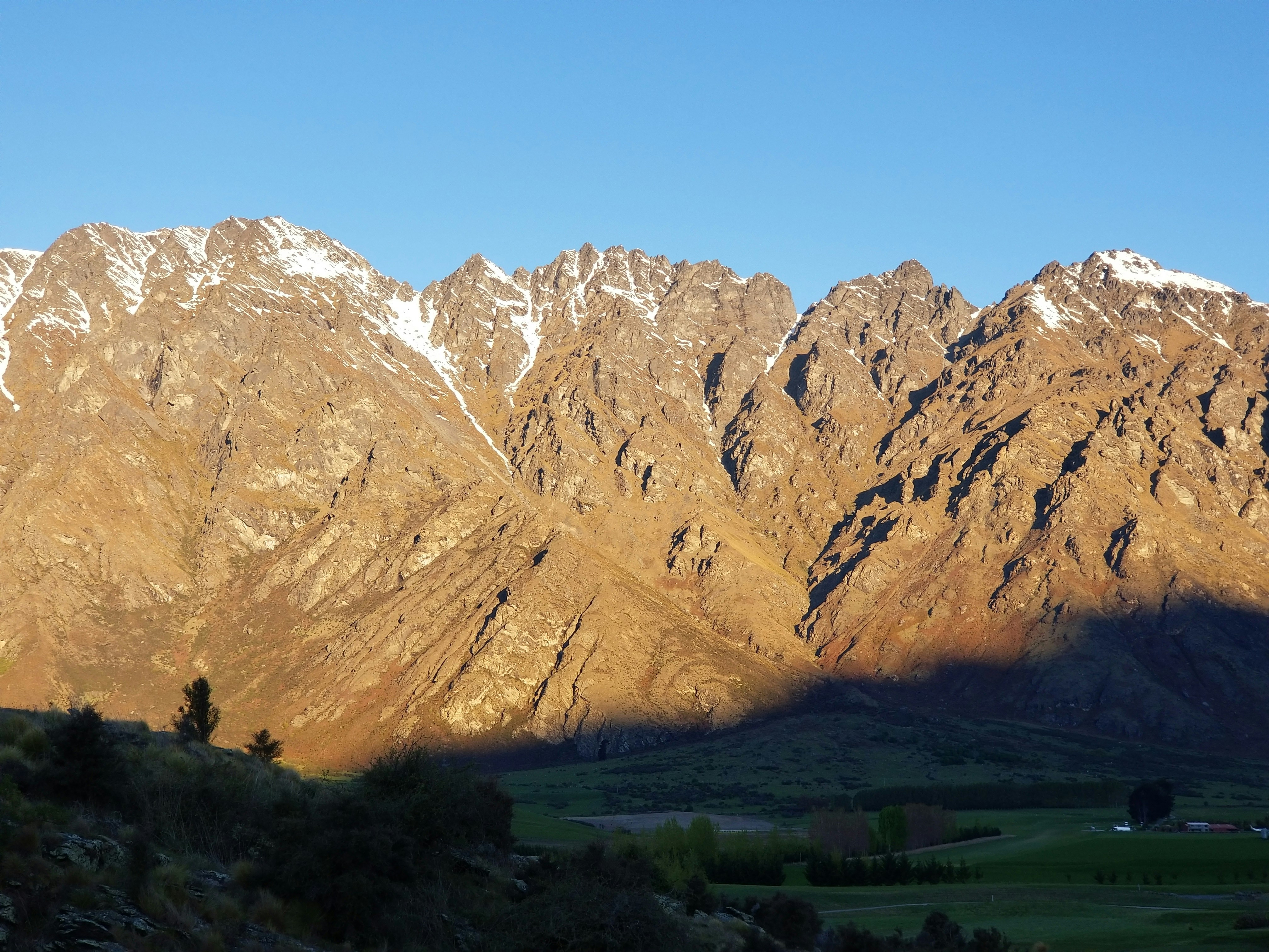 une vue d’une chaîne de montagnes avec le soleil qui brille dessus
