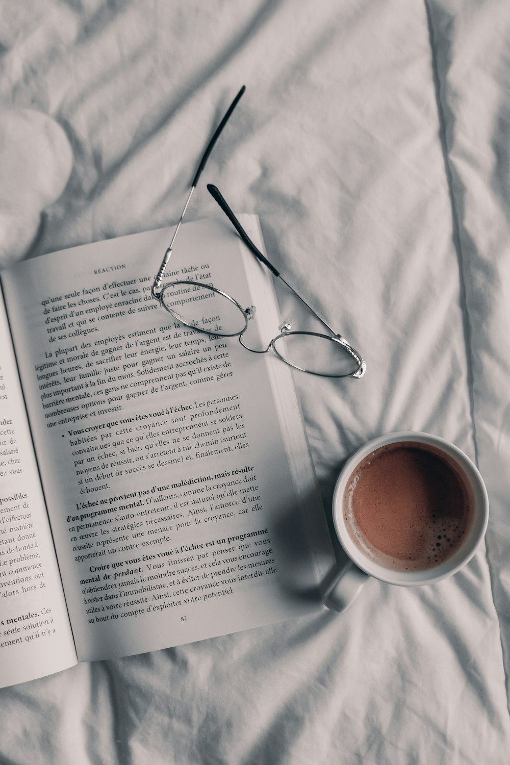 une tasse de café et un livre sur un lit