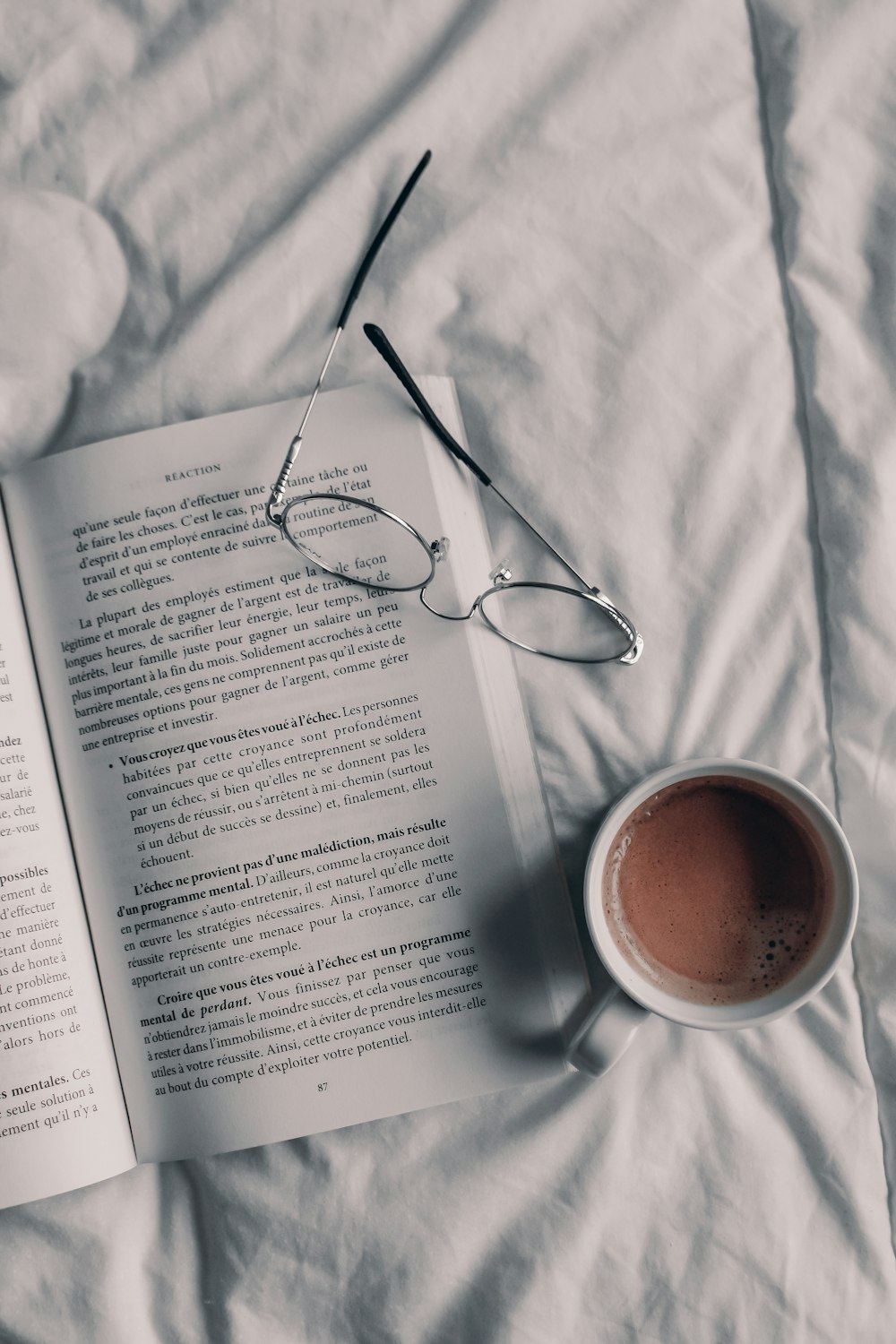 a cup of coffee and a book on a bed