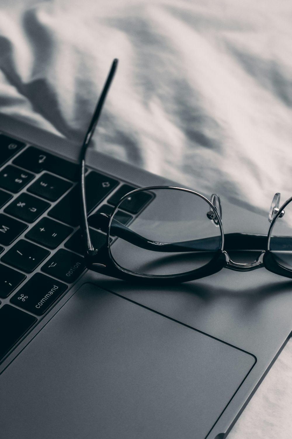 a pair of glasses sitting on top of a laptop computer