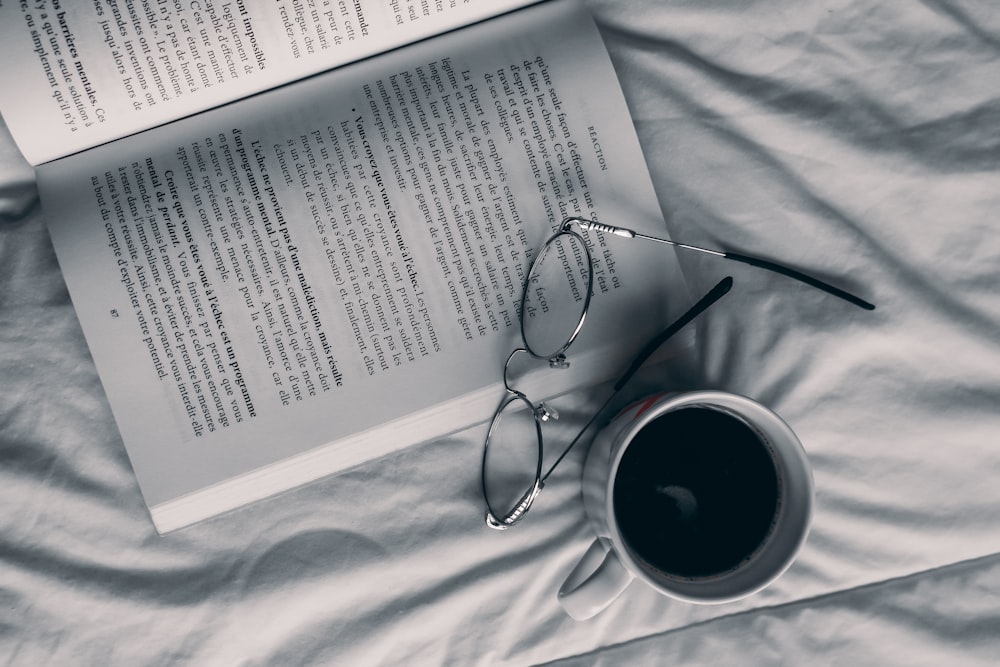 una taza de café y un libro en una cama