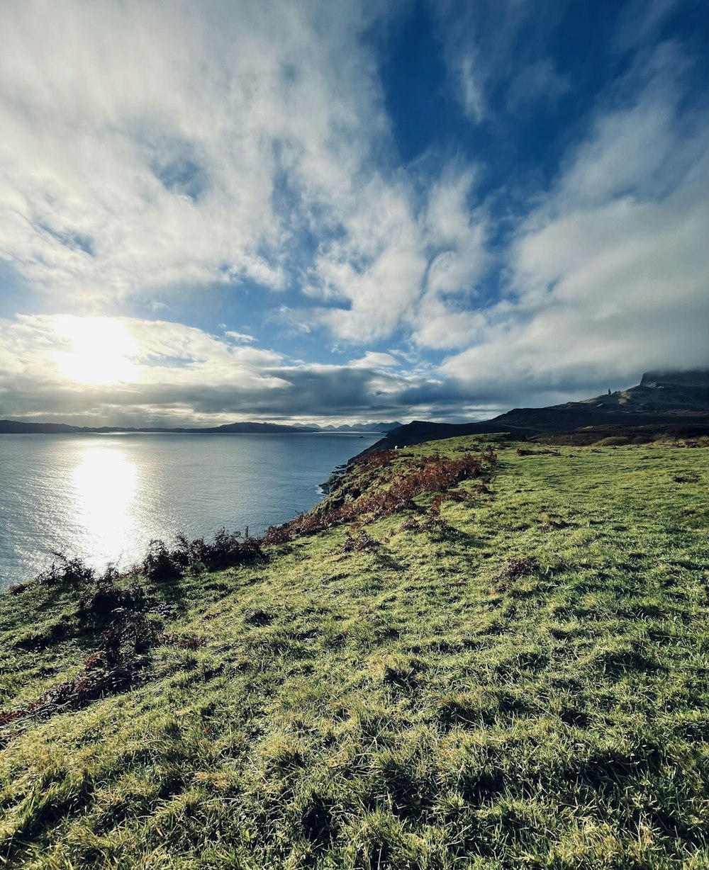 a grassy hill with a body of water in the background