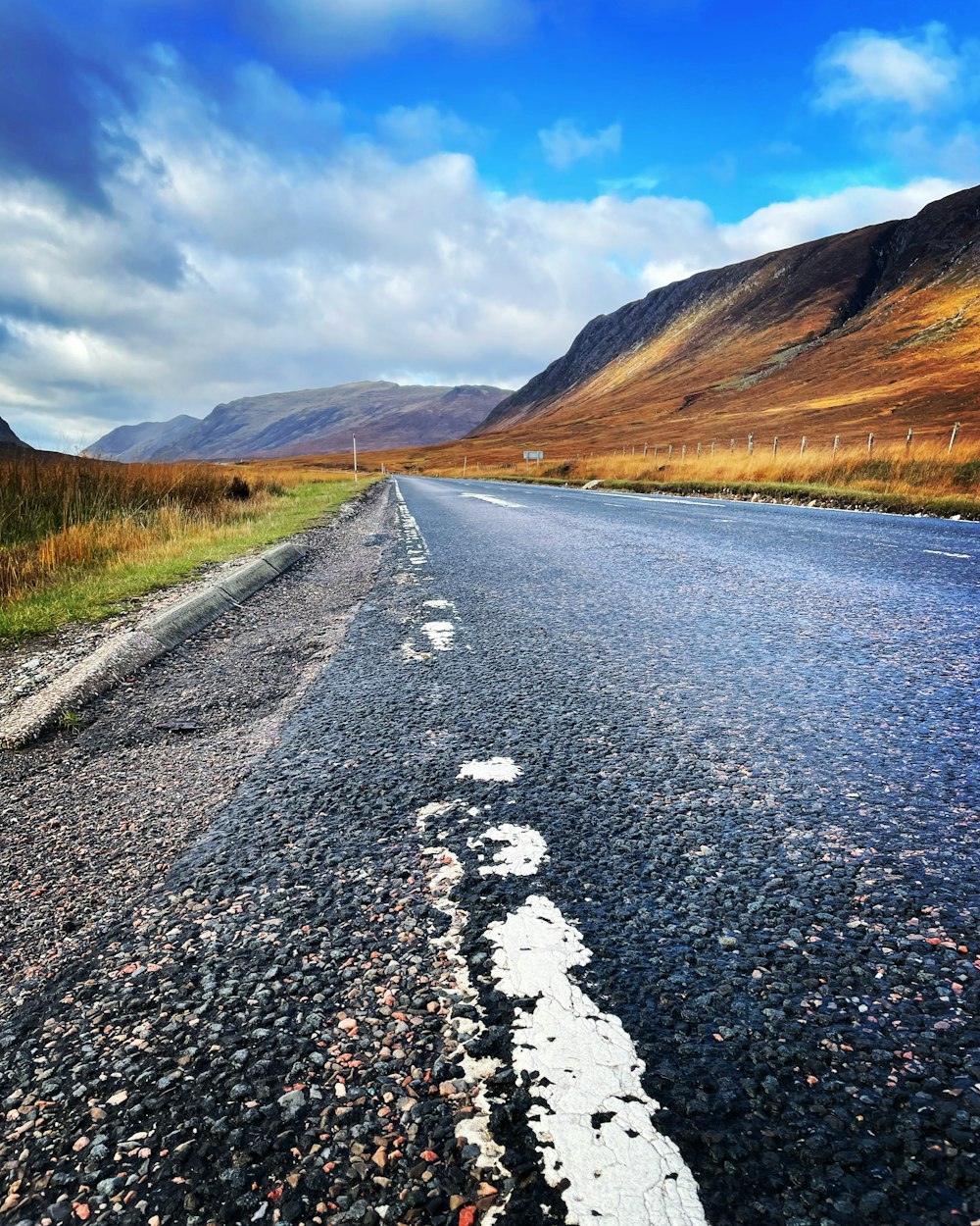 an empty road in the middle of a mountain range