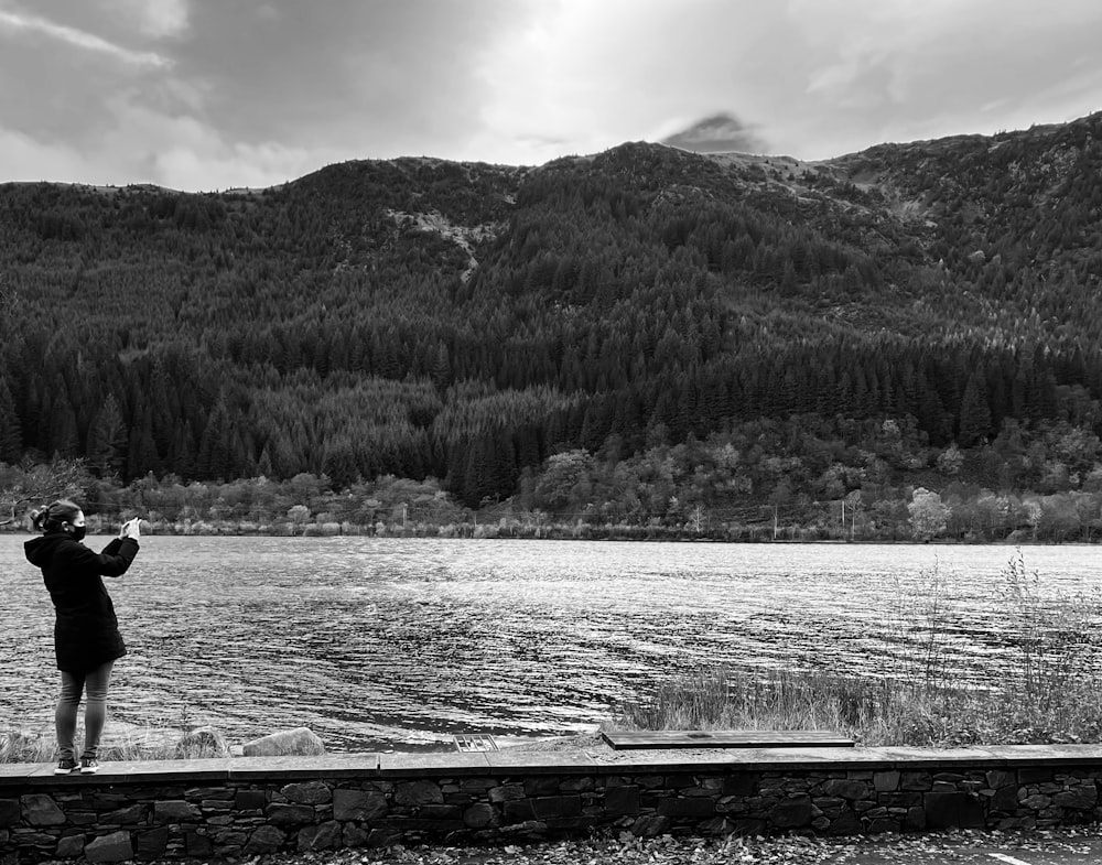 a person taking a picture of a mountain lake