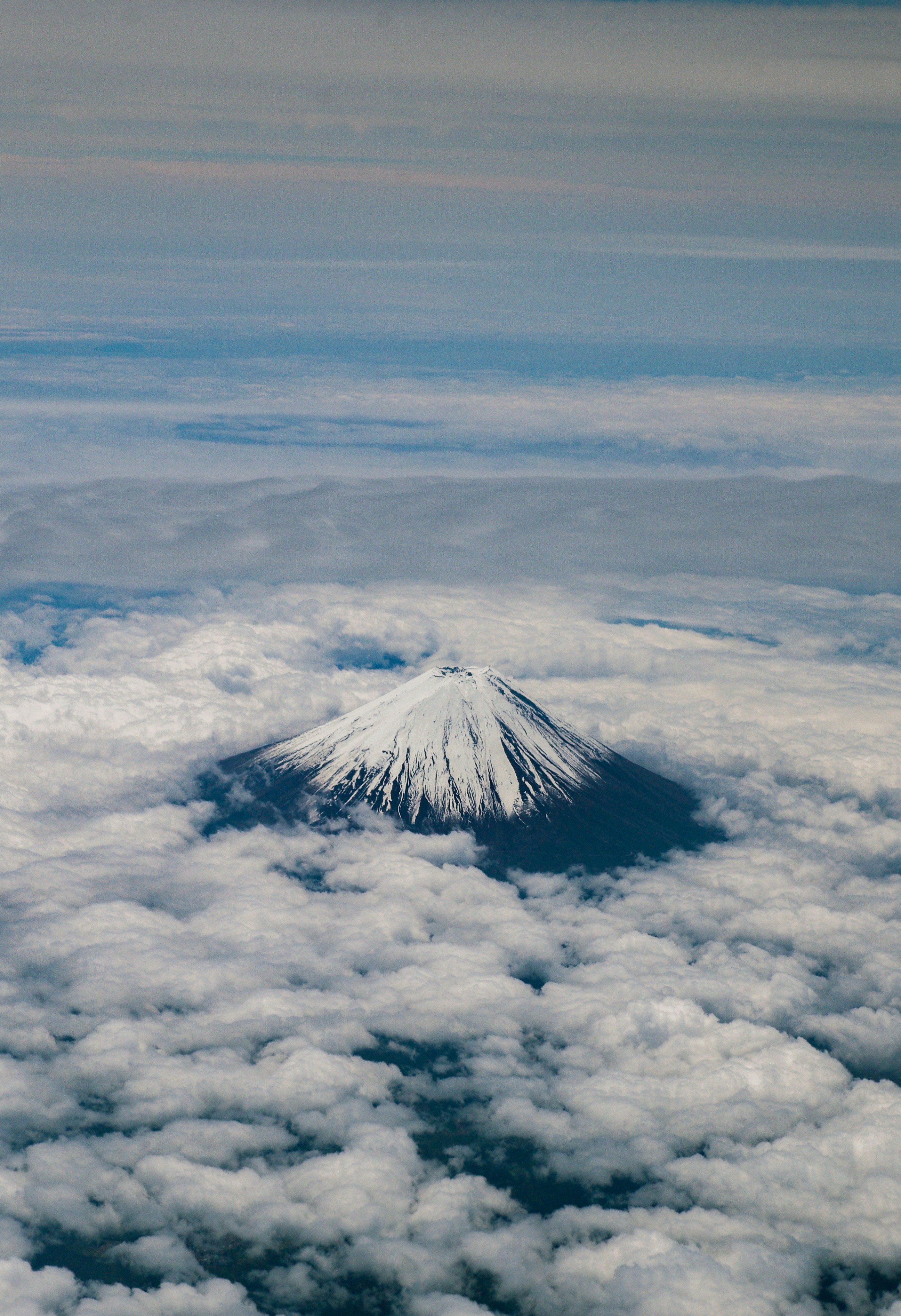a view of a snow capped mountain in the clouds