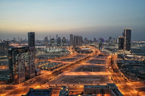 Aerial view of a modern city skyline with sleek glass buildings at dusk.