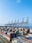 A busy shipping port with containers and cranes under clear skies.