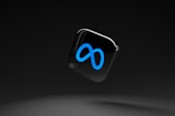 A sleek, black background with a floating glossy black square featuring a prominent blue infinity symbol.