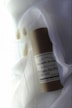 A cylindrical container labeled 'Zielinski & Rozen Perfume' rests on a soft, white fabric background. Delicate, dried pampas grass stems are placed beside it, adding an organic touch. The overall composition appears minimalist and elegant.