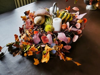 a table topped with lots of different types of flowers, candles and fall decorations