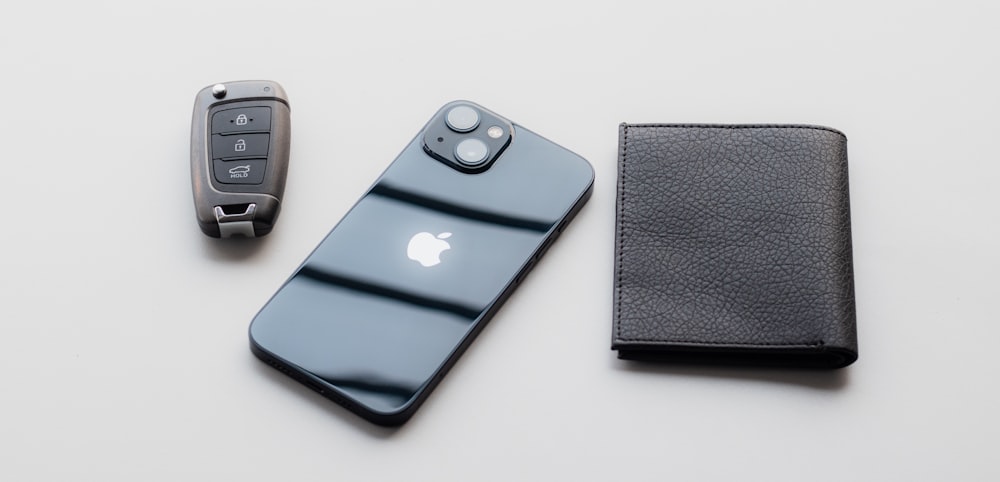 a cell phone sitting next to a wallet and a car key