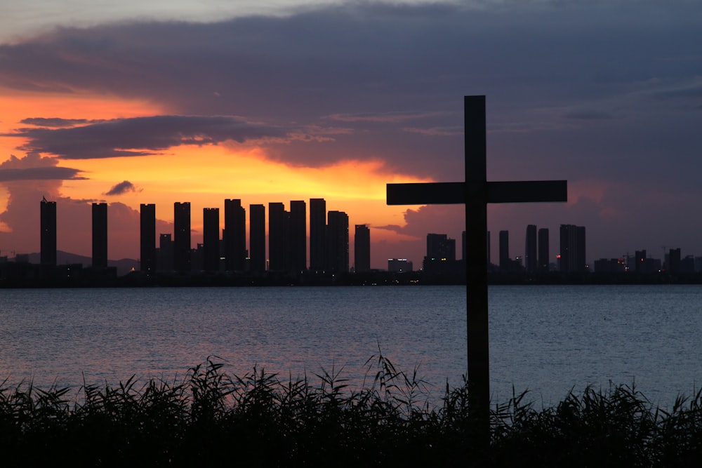 a cross in front of a body of water with a city in the background