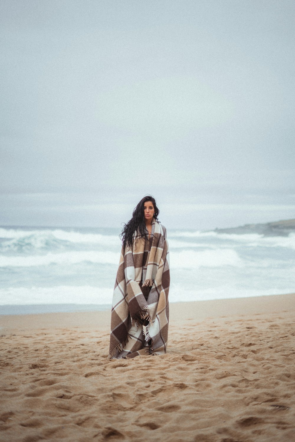 a woman wrapped in a blanket on a beach