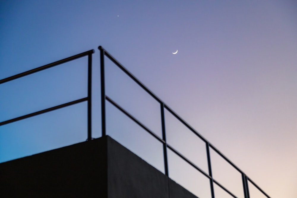 a view of a fence and a half moon in the sky