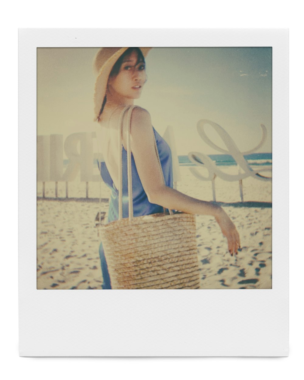 a woman walking on a beach carrying a basket