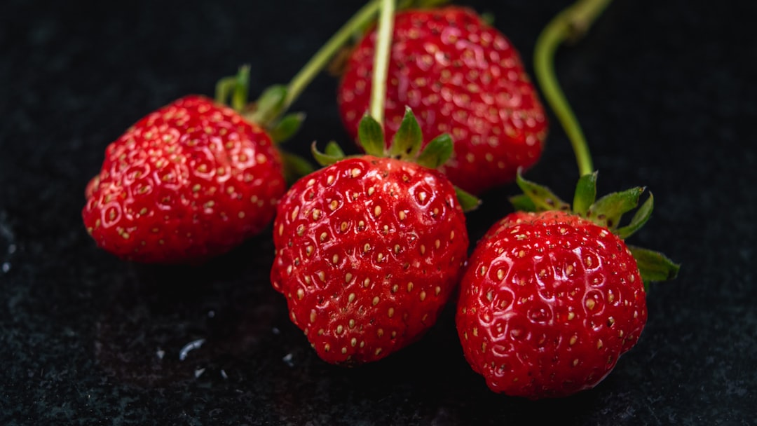 a group of three strawberries sitting on top of a table,