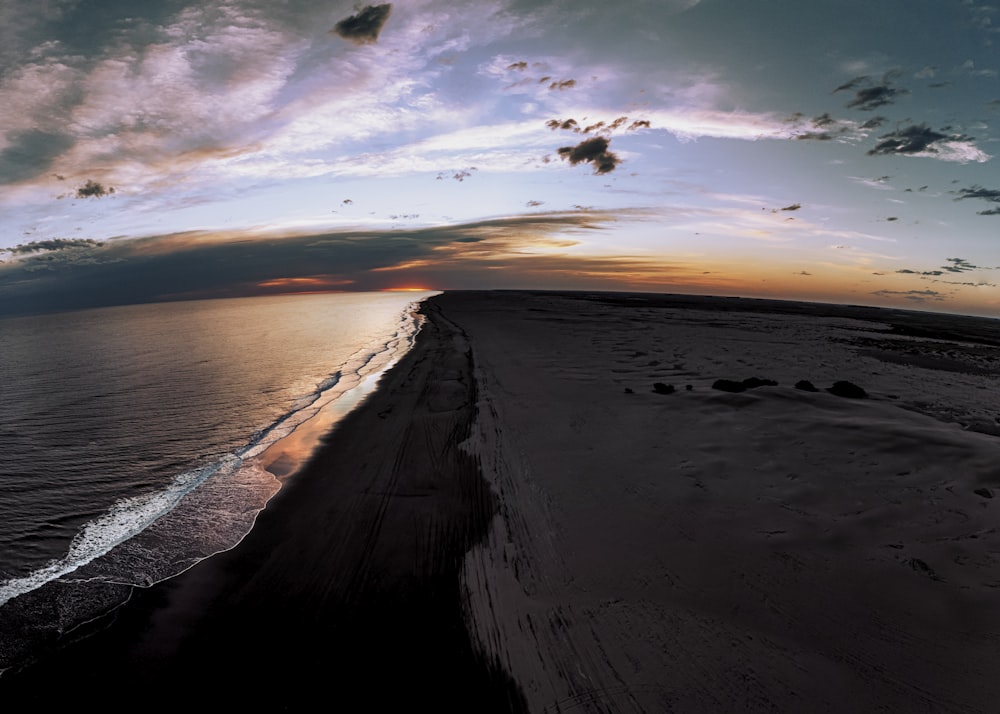 the sun is setting over the ocean on the beach