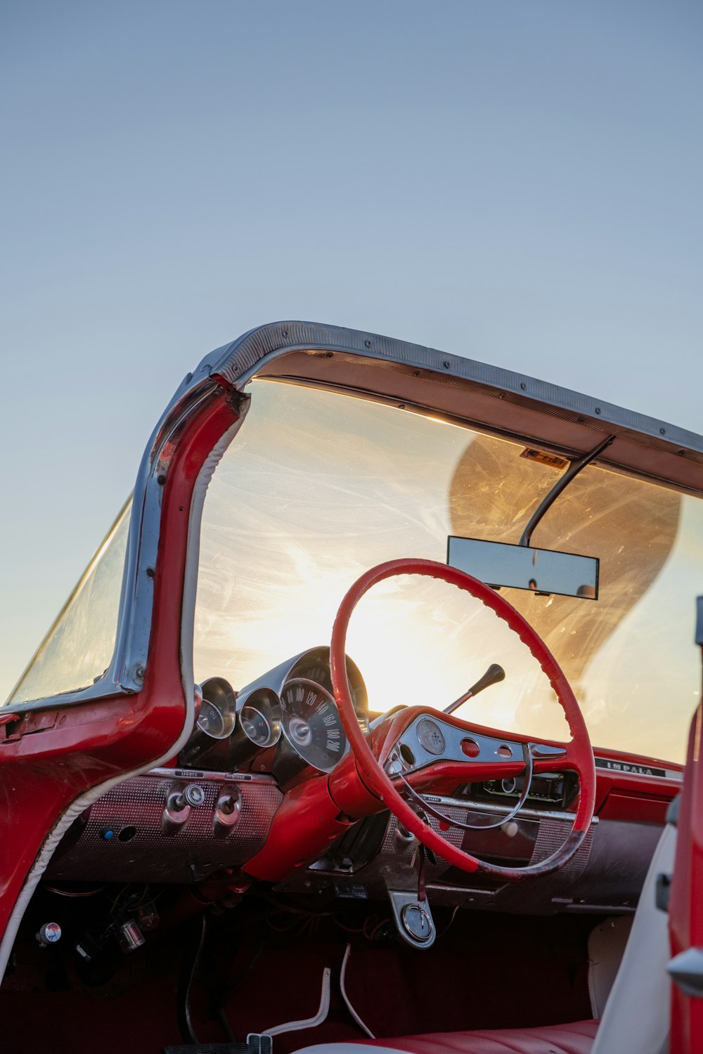 the inside of a red car with a steering wheel