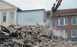 a bulldozer digging through a pile of rubble in front of a building