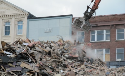a bulldozer digging through a pile of rubble in front of a building