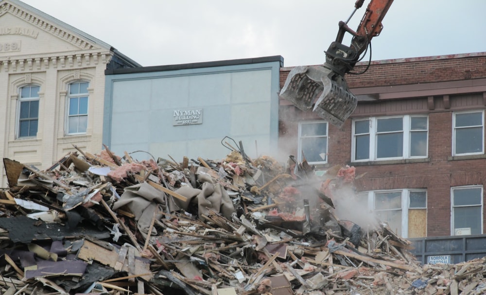 a bulldozer digging through a pile of rubble in front of a building