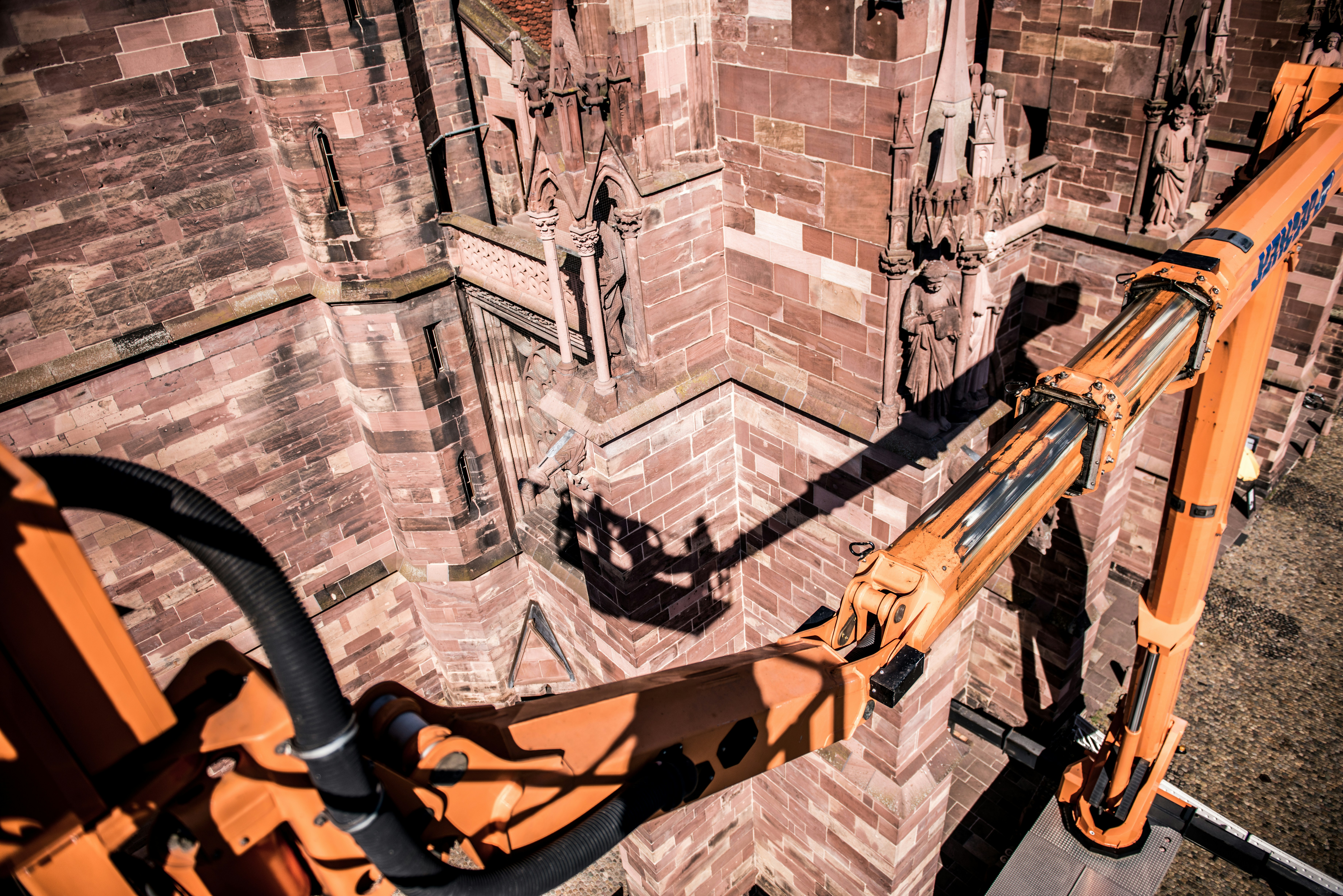 a large orange crane is on a brick wall