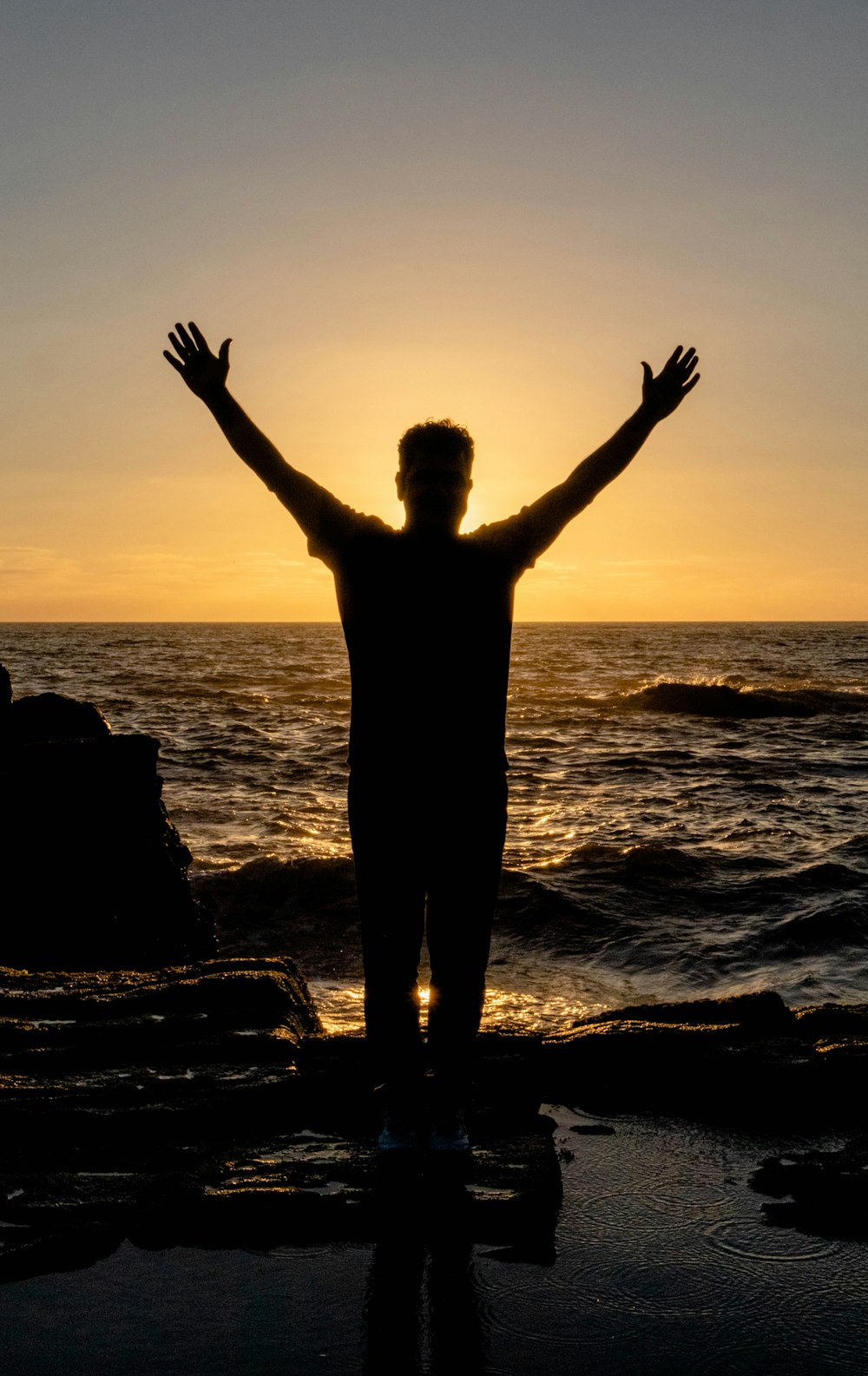 a person standing on a beach with their arms outstretched