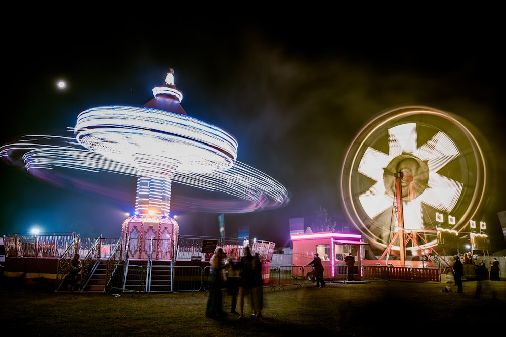 a fairground with a carousel and a spinning wheel at night
