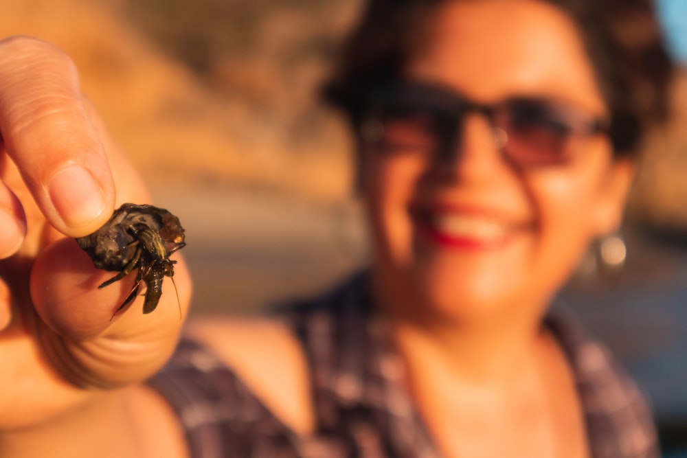 a woman holding a small insect in her hand