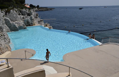 a person standing in a pool next to the ocean