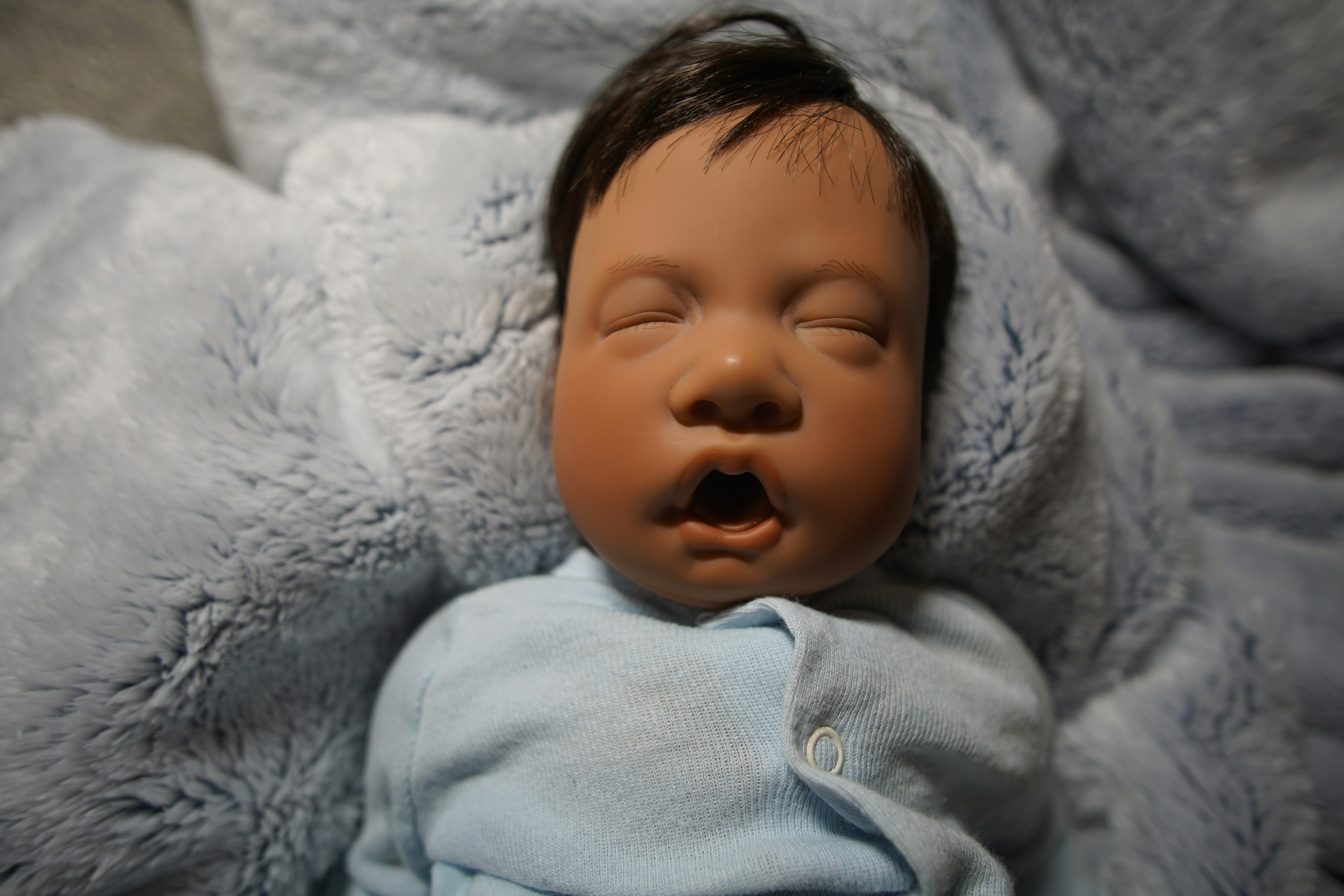 a baby doll that is laying down on a blanket