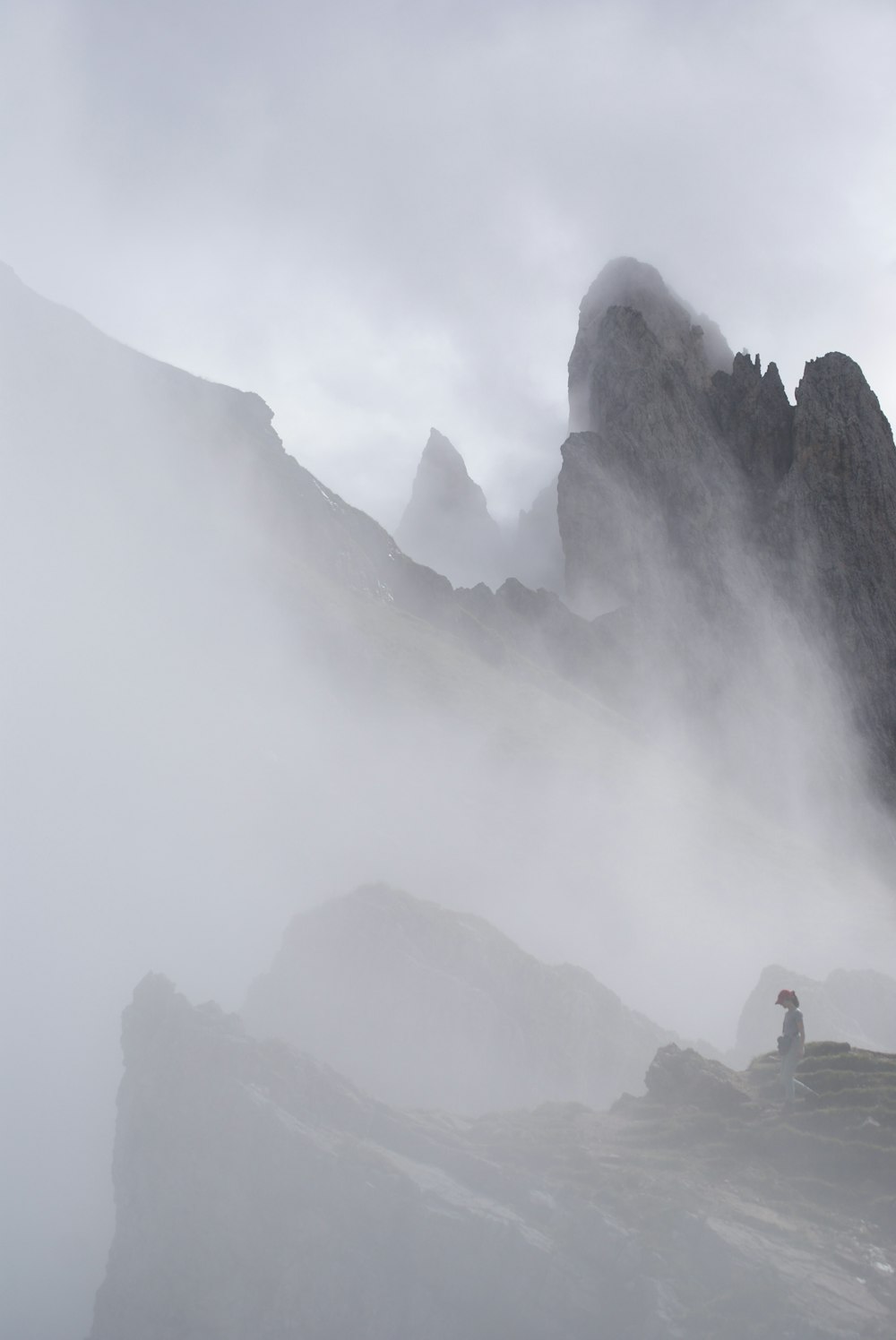 a foggy mountain with a person sitting on a rock