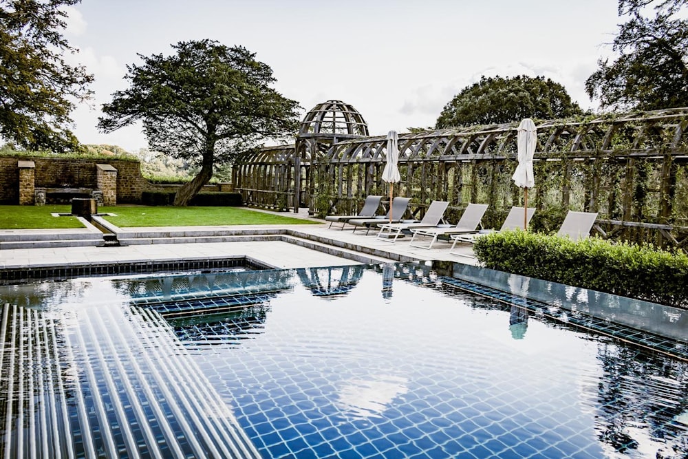 a swimming pool surrounded by lawn chairs and trees