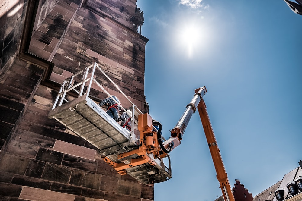 a man on a cherry picker working on a brick building