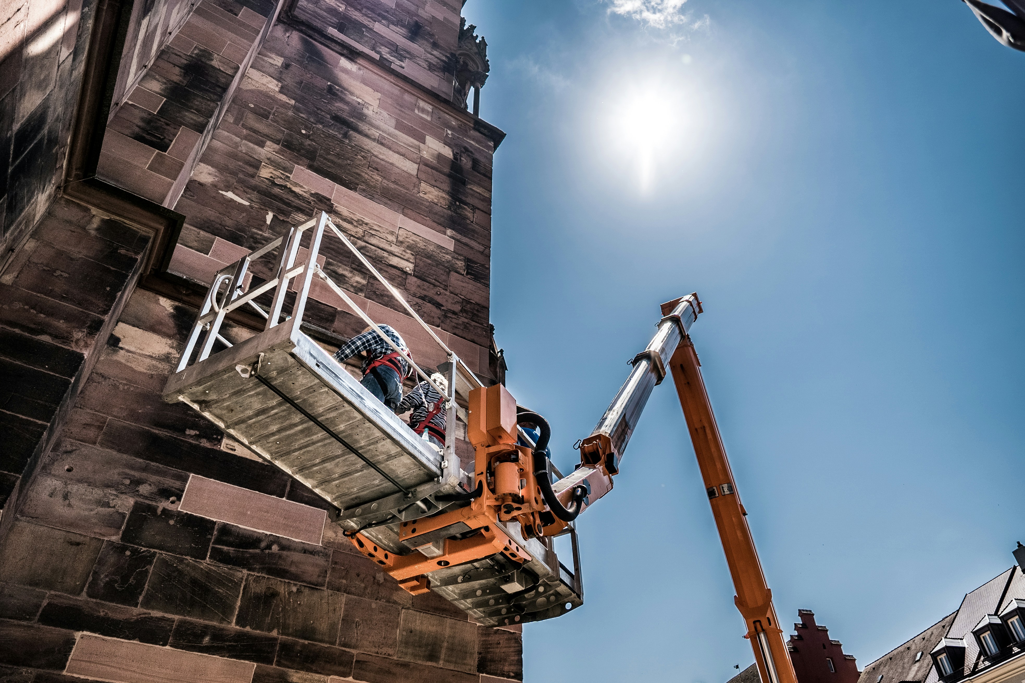 a man on a cherry picker working on a brick building